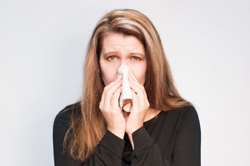 Sad woman fell ill and wiped the nose with a handkerchief. Woman has allergies to spring flowers because they bloom