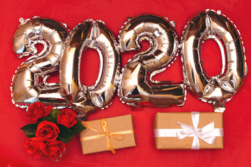 2020 ballon numbers isolated on red background with red roses and boxes gift, new year concept