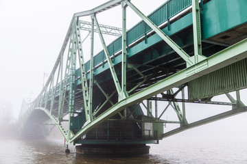 An old bridge is visible across the canal mist