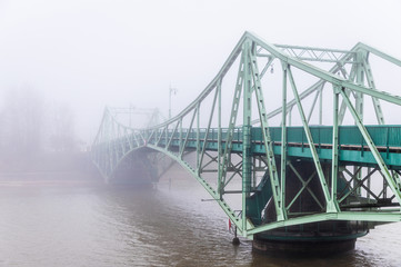 An old bridge is visible across the canal mist