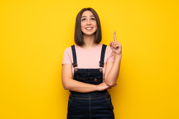 Young woman over yellow wall pointing with the index finger a great idea