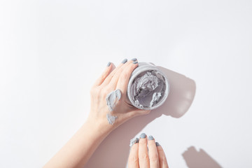 Natural face and body mask in container in woman hands