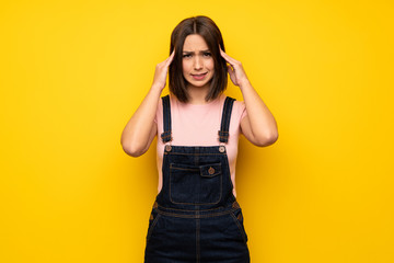 Young woman over yellow wall with headache