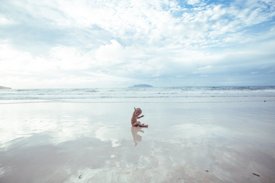 Naked baby girl sitting on the beach, Seychelles