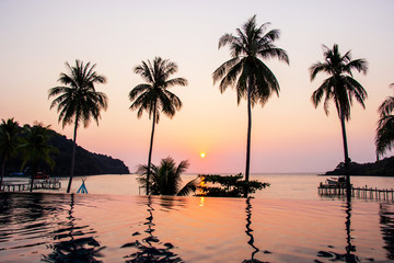 Fototapeta premium Sunset reflecting on the water surface foreground with coconut trees area ao bang bao at Koh kood island is a district of Trat Province. Thailand.