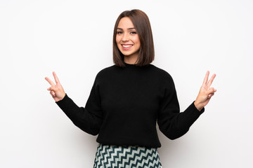 Young woman over white wall smiling and showing victory sign with both hands