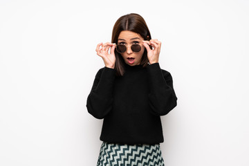 Young woman over white wall with glasses and surprised