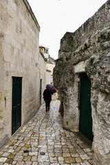Narrow street with rough rock wall and one person with a umbrella - 251033708