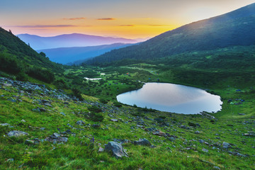 Summer in the Carpathian massif of Swidovets, located in Ukraine, with a lot of lakes, green pasture for sheep and horses, and wonderful, after a stormy sky with a rainbow.