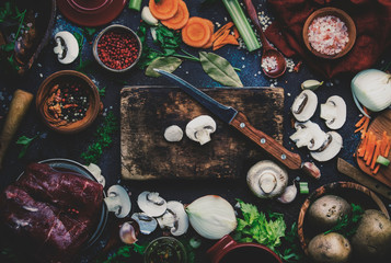Fresh organic vegetables, ingredients, spices and meat for soup or broth on vintage kitchen table background with rustic wooden cutting board. Top view, place for text