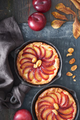 Homemade crumble tarts with plum slices baked in small iron skillets