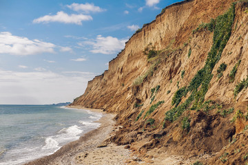 Beautiful view of sandy cliff near sea beach. Landscape of beach cliff and waves. Summer vacation concept. Exploring interesting places