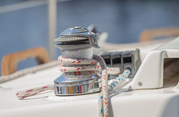 Sailboat winch with rope on yacht deck.