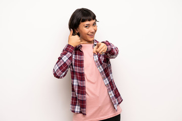 Young woman with short hair making phone gesture and pointing front