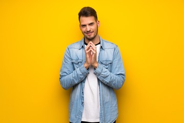 Handsome man over yellow wall scheming something