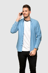 Fototapeta premium Handsome man keeping a conversation with the mobile phone over grey background