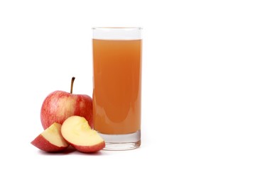 apple juice - sliced ​red apples and a glass of naturally cloudy apple juice in front of white...