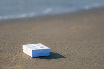 Fototapeta na wymiar White gift box on the sand on a beach.