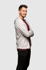 Man with sweatshirt with arms crossed and looking forward over grey background