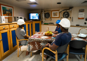 Seamen crew onboard a ship or vessel having fun watching TV. Recreation during at sea