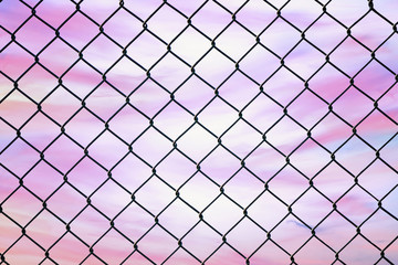 Fototapeta premium Conceptual image of twilight sky with effect of light pastel tone and steel mesh wire fence. Concept of hope and freedom