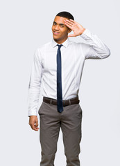 Young afro american businessman saluting with hand on isolated background