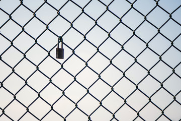 Mesh wire fence with lock on the sky background. Isolated.