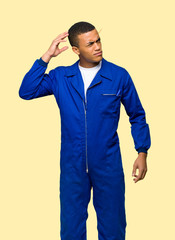 Young afro american worker man having doubts while scratching head on isolated background