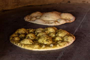 Italian bread rolls - in the foreground with chili, pesto with basil and olive oil and the other - ground paste and olive oil. In a stone furnace.