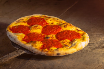 Italian Focaccia with tomato sauce and oil on the shovel in a stone furnace.