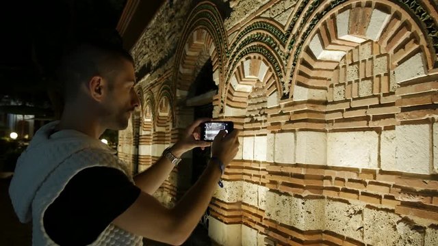 Young man taking photos of ancient european temple