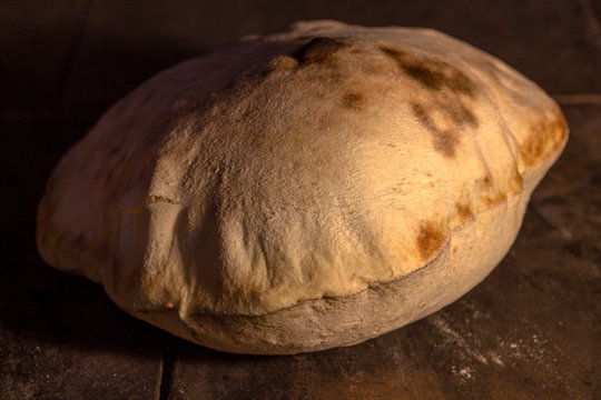 A close-up of Turkish bread baked in a stone oven. When cooked, it stays hollow from the inside.