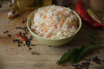sauerkraut in a bowl on a wooden table with oil in a bottle, spices and herbs