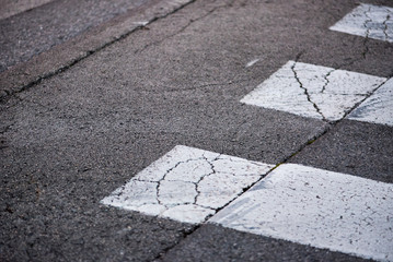 Damaged asphalt on the roadway and on pedestrian zebra crossing, abstract background