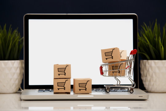 paper boxes in a shopping cart on a laptop keyboard. Concepts about online shopping that consumers can buy things directly from their home or office just using a few clicks via web browser.