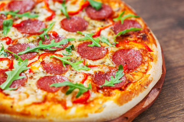 Pepperoni Pizza with Mozzarella cheese, salami, Tomatoes, pepper, Spices and Fresh arugula. Italian pizza on wooden table background