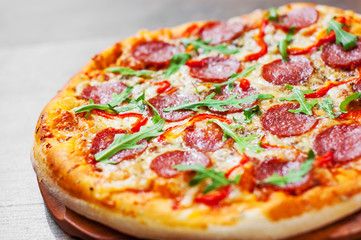 Pepperoni Pizza with Mozzarella cheese, salami, Tomatoes, pepper, Spices and Fresh arugula. Italian pizza on wooden table background