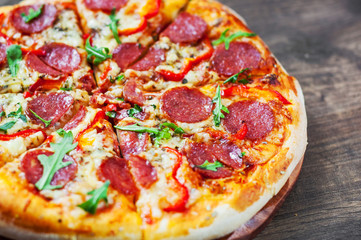 Pepperoni Pizza with Mozzarella cheese, salami, Tomatoes, pepper, Spices and Fresh arugula. Italian pizza on wooden table background