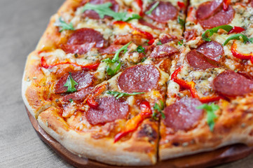 Pepperoni Pizza with Mozzarella cheese, salami, Tomatoes, pepper, Spices and Fresh arugula. Italian pizza on wooden table background