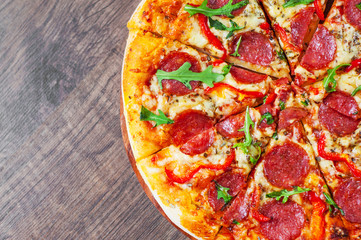 Pepperoni Pizza with Mozzarella cheese, salami, Tomatoes, pepper, Spices and Fresh arugula. Italian pizza on wooden table background