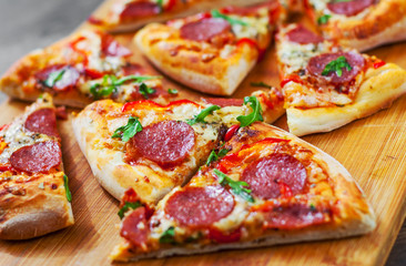 Pepperoni Pizza with Mozzarella cheese, salami, Tomatoes, pepper, Spices and Fresh arugula. Italian pizza on wooden table background