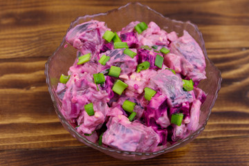 Tasty salad with herring, beetroot, eggs, onion and mayonnaise on wooden table