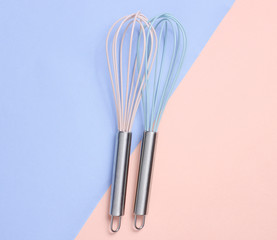 Two whisk on blue pink pastel background. Top view, minimalism.