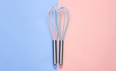Two whisk on blue pink pastel background. Top view, minimalism.