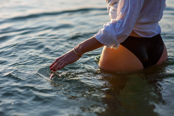 Female lower body in bikini and white shirt in the sea waves