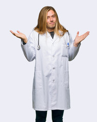 Doctor man making unimportant gesture while lifting the shoulders on isolated background