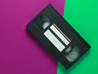 Retro video cassette on pink green background. Top view.