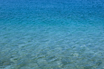 Blue transparent sea water texture. Bright ocean water background. Summer holiday concept.