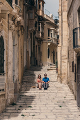 Fototapeta na wymiar Man and woman sitting on the stairs on the street