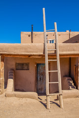 Ladder leading to second story apartments on traditional mud adobe pueblo with porch and old grunge...